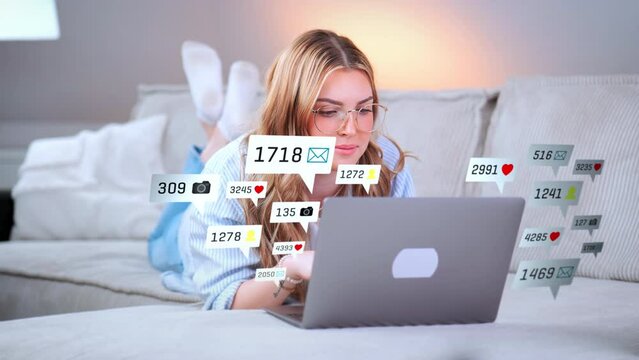 Young woman relaxed on her sofa visiting social media sites and apps on her notebook computer. Digital Overlay Counter Symbols of Hearts, Messages, Likes, Photos and Persons