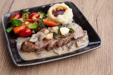 Pork shoulder steak with mushroom sauce, mashed potatoes and grilled vegetable