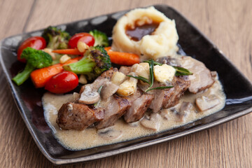Pork shoulder steak with mushroom sauce, mashed potatoes and grilled vegetable