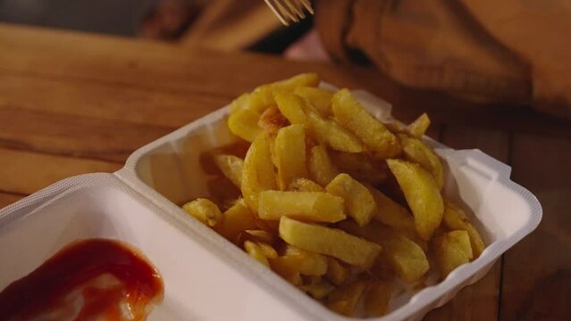 People at festival enjoying a Styrofoam box of French fries and tomato sauce
