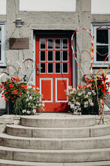 Rote Tür eines Standesamtes mit Blumen geschmückt
