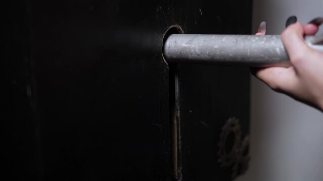 Close-up of a woman opening the door lock with a huge metal key in the quest room. Completing an Alice in Wonderland-style quest.