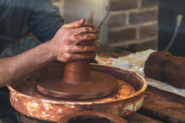 The skillful hands of a potter form a product on a potter's wheel. Traditional crafts. DIY ceramics.