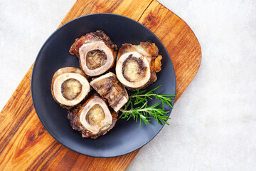 Roasted Marrow bones on a black plate with rosemary garnish