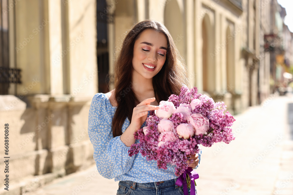 Poster Beautiful woman with bouquet of spring flowers on city street