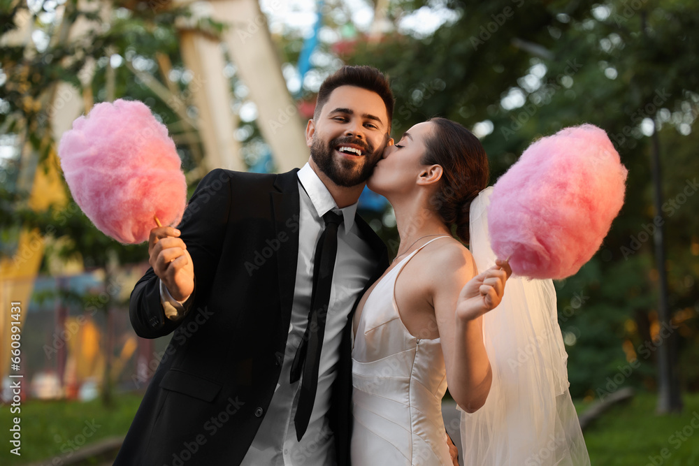 Wall mural Happy newlywed couple with cotton candies outdoors