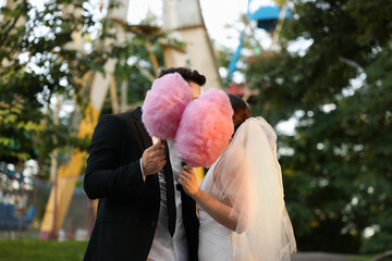 Newlywed couple with pink cotton candies outdoors