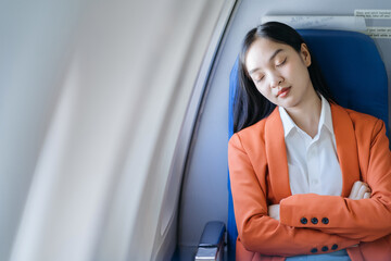 Tired asian woman with headache feeling sick while sitting in the airplane , Passengers near the window.