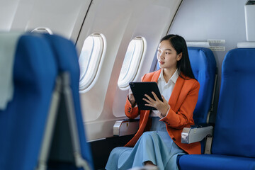 Traveling and technology. young business woman working on Tablet while sitting in airplane. - obrazy, fototapety, plakaty
