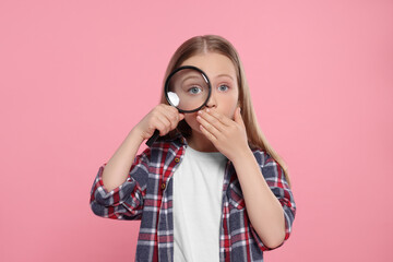 Cute little girl looking through magnifier on pink background