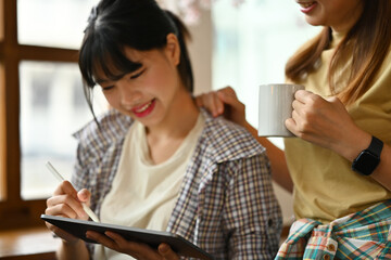 Happy asian woman using digital tablet, sharing ideas or new information to her colleague