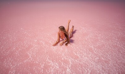 Woman in a pink salt lake. She lies in a white bathing suit. Wanderlust photo for memory