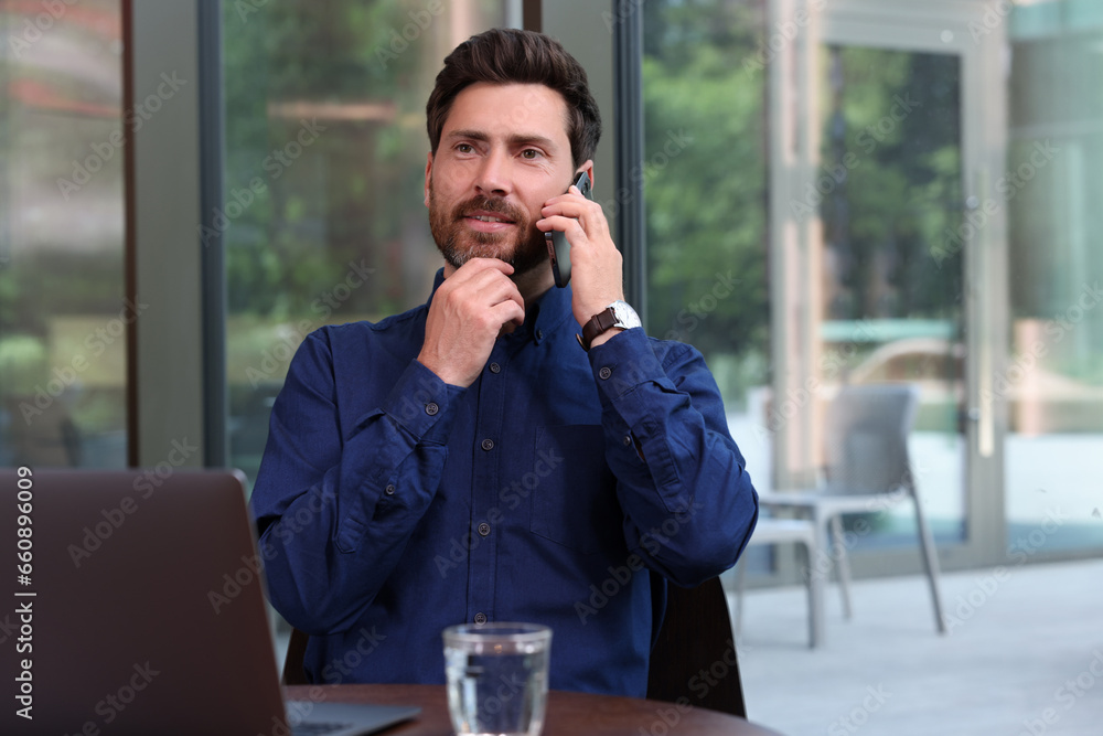 Canvas Prints Handsome man talking on phone at table indoors