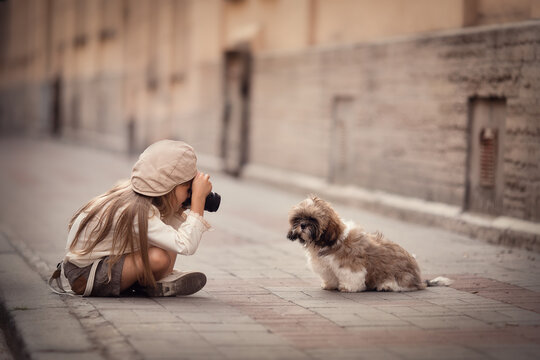 Little girl with camera and puppy taking photos on the streets of the city 