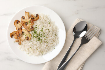 Delicious rice with parsley and mushrooms served on white marble table, flat lay