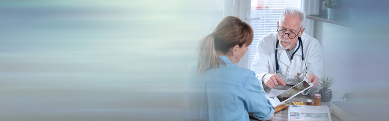 Doctor showing reports on digital tablet to his female patient; panoramic banner