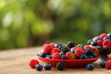 Different fresh ripe berries on wooden table outdoors, space for text