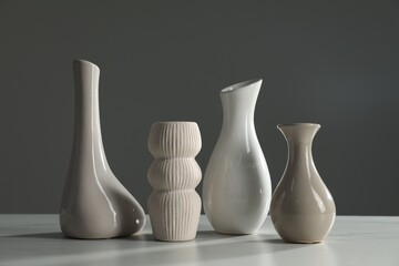 Different stylish vases on white marble table