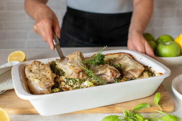 Healthy fish casserole with brown rice and broccoli is served with a spatula by a woman´s hand with apron