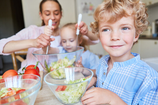 Smiling boy with mother and daughter preparing salad
