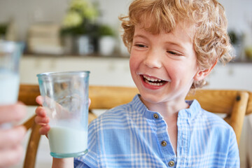 Cute boy toasting milk glass with mother