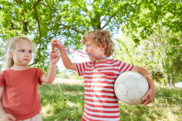 Boy showing medal to sister in garden - Powered by Adobe