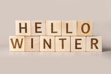 The Word Hello Winter on wooden cubes on a beige neutral studio background. Copy Space. Written. Text words matter. Christmas decorations. Inscription Happy New Year business concept strategy Start Up