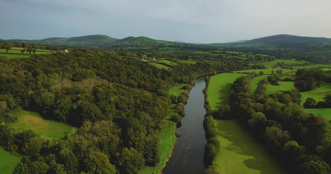 A 4K drone reveal shot of The River Nore flowing slowly towards the village of Inistioge County Kilkenny Ireland with the bridge leading to the village a short distance away Sheep graze nearby