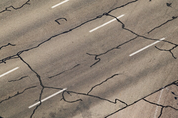 The road surface is filled with squiggly tar crack filler. Cracks in the asphalt surface of a...