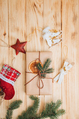 Christmas background. Gifts wrapping in brown paper with dry orange and branch of coniferous tree on a light wooden background. Top view