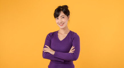 Obraz premium portrait cheerful young asian woman 30s wearing purple shirt happy smile crosses arm on chest isolated on yellow background.