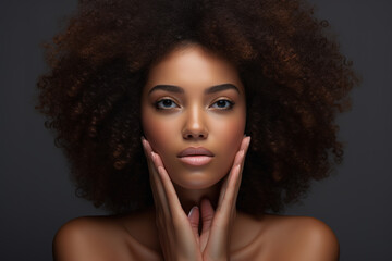 Headshot of attractive African American woman model with curly afro hair and pure clean skin. Looking at camera, isolated on dark grey background.