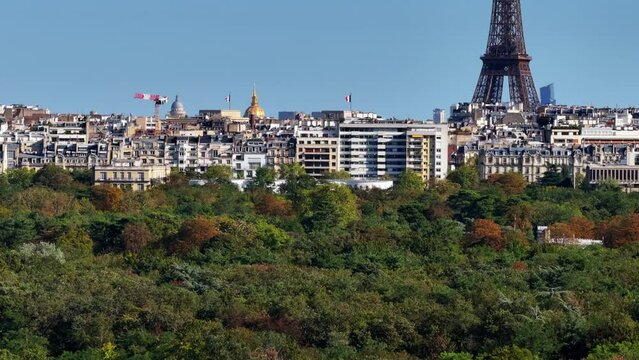 Aerial view of trees in park and surrounding buildings. Rising reveal of panoramic view of historic city center. Paris, France