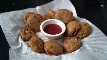 Pakora or pakoda, a traditional and popular Indian vegetarian snack, in a tray.