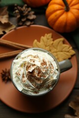 Flat lay composition of tasty pumpkin spice latte with whipped cream in cup on wooden table