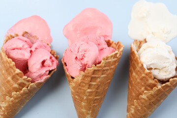 Melted ice cream in wafer cones on light blue background, flat lay