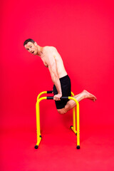 Front and side view photo of an strong young man exercising on parallel bars in studio.