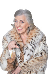 portrait of beautiful senior woman in fur coat showing something