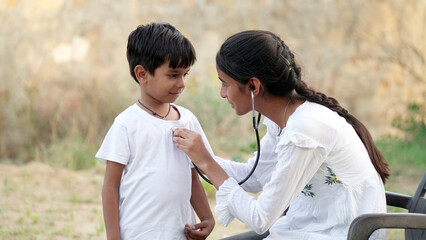 Female doctor or pediatrician with stethoscope listening to heartbeat boy's patient on medical exam...