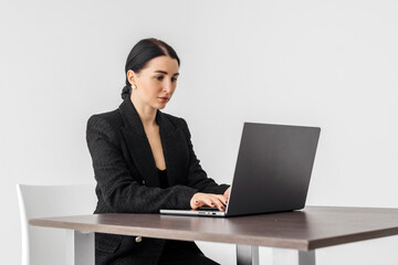 A business woman banker works in a bright room at a laptop. Concept for business style clothing, loan, finance and technology.