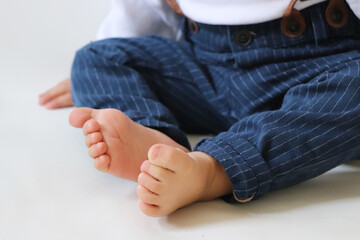 Close up baby boy feet. Baby boy feet with blue trousers isolated on white background. Selective Focus.