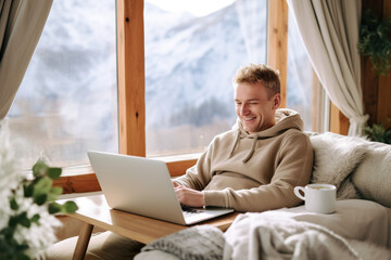 Man Smiling at Laptop in Cozy Cabin with Mountain View - obrazy, fototapety, plakaty