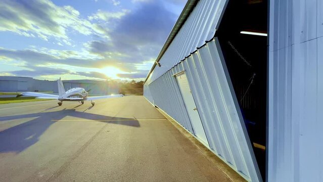hangar door opens as sun sets, sunset with piper cherokee 180 on tarmac