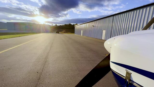sunset push in beyond prop of piper cherokee 180 on tarmac outside hangar
