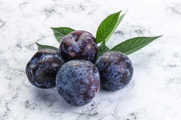 Raw purple plums heap with leaves