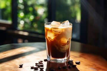 A refreshing glass of iced nutmeg coffee sits on a rustic wooden table, bathed in the soft glow of morning light filtering through nearby windows