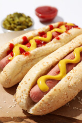 Hot dogs and sauces in bowls on white background, close up