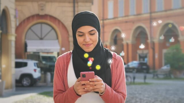 muslim female girl walking using smart phone browsing social media network,3d graphic emoticon icons visualization coming out from the smartphone screen