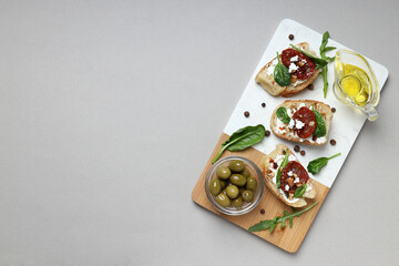 Fototapeta na wymiar Toast with sun-dried tomatoes on a board, on a gray background.