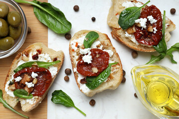 Toast with sun-dried tomatoes on a board, on a gray background.